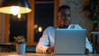 © Akmalism - Serious thoughtful young African freelance business man working at laptop computer, sitting at table on floor, looking away in deep thoughts, thinking on creative ideas, making decision.