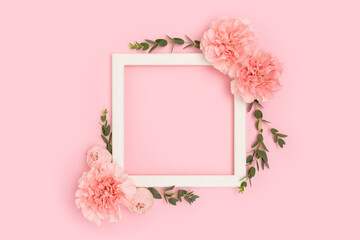 Wall Mural - square frame made of carnation flowers and green eucalyptus branches on a pink background. place for