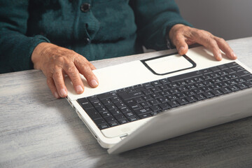 Hands of elderly woman typing in computer keyboard.