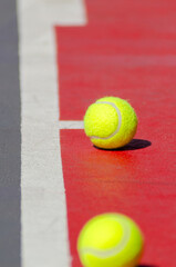 two tennis balls next to the line of a tennis court