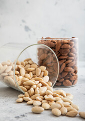 Wall Mural - Glass jars with healthy raw almond whole and peeled nuts on white kitchen table.Macro.