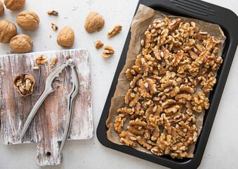 Wall Mural - Baking tray with raw peeled walnut nuts with cracker on light kitchen background.Macro.