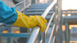 © Creator - A man is cleaning the handrails of a staircase with a sponge and gloves. Close up of his hand.