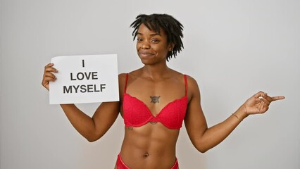 Poster - Joyful young black woman with dreadlocks, expressing love for her body, confidently points and smiles to the side against a white isolated background