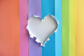 Ripped paper hole heart shape over rainbow color background. Love, LGBT, pride concept.
