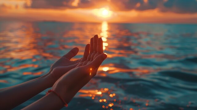 Two hands reaching out into the ocean, with the sun setting in the background
