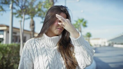 Poster - Hispanic woman in sweater shading eyes outdoors