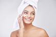 © peopleimages.com - Happy woman, skincare and moisturizing with cream or ointment for hygiene on a gray studio background. Face of female person or model with smile for lotion, anti aging or healthy facial treatment