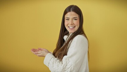 Poster - Cheerful young hispanic woman donning sweater, pointing to copy space happily! captivating ad presentation showing open palms against isolated yellow background.