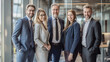 © Tetiana - Diverse team of business professionals standing together in a modern office, dressed in formal business attire, smiling confidently. teamwork and success concept