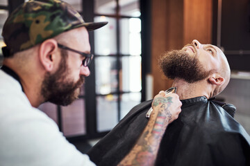 Beard, shave and man in barbershop with machine, client and tools for trendy facial cut at small business. Style, barber and customer in chair for grooming service, haircut skills and clean trim