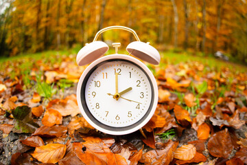 Wall Mural - Alarm clock with autumn foliage, end of daylight saving time in fall, winter time changeover