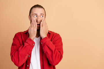 Wall Mural - Photo of nice young man stare empty space wear red shirt isolated on beige color background