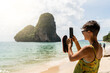 © Alvaro Lavin/Stocksy - Woman taking photos on the beach.