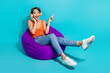 © deagreez - Full size photo of crazy astonished girl sit on bean bag touch headphones directing at sale empty space isolated on blue color background