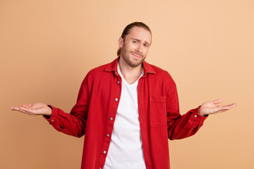 Poster - Photo of nice young man shrug shoulders wear red shirt isolated on beige color background