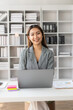 © ArLawKa - Asian businesswoman sits behind a desk looking at a monitor with a stock market graph tracking market prices. Big data analysis helps business in modern business office