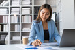 © ArLawKa - Asian businesswoman sits behind a desk looking at a monitor with a stock market graph tracking market prices. Big data analysis helps business in modern business office
