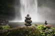 © Pedro Merino/Stocksy - stack of stones balanced in front of a waterfall