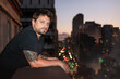 © Luciano Spinelli/Stocksy - Tattooed young man enjoying his apartment balcony in nightfall