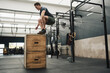 © Nicola Suttle/Stocksy - Focused young male athlete jumping on wooden box in gym