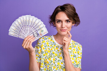 Canvas Print - Portrait of pretty young woman hold cash think wear t-shirt isolated on purple color background