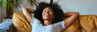 © Daniel - Happy afro american woman relaxing on the sofa at home - Smiling girl enjoying day off lying on the couch - Healthy life style, good vibes people and new home concept