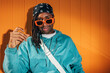 © VICTOR TORRES/Stocksy - Stylish black man in hip-hop attire posing against orange backdrop