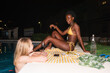 © Milles Studio/Stocksy - Multiracial friends talking at poolside in the night
