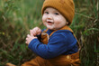 © Serena Burroughs/Stocksy - little infant baby boy sitting in grass in autumn