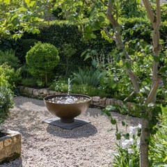 Wall Mural - A large, ornate fountain sits in a garden with a stone wall