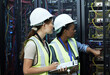 © peopleimages.com - Inspection, women and computer engineer with pointing in data center for teamwork or collaboration. Female people, clipboard and tech hardware security in server room for system update or maintenance