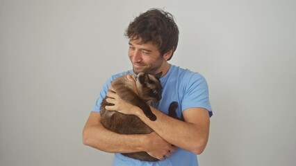 Wall Mural - A young man affectionately embraces a loving siamese cat against a white background