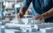© OLGA - Architect working on a detailed building model with blueprints.