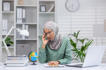 Tired and tired online teacher, woman in hijab working in home office remotely, teaching students and pupils, using laptop at work