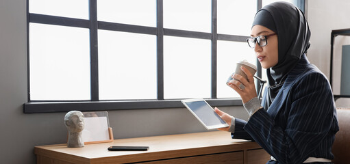 Sticker - Muslim businesswoman with tablet computer and cup of coffee at table in office