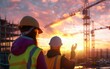 © OLGA - Engineers in hard hats inspecting a construction site at sunset.