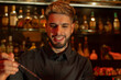 © Omar - Young elegant barman working behind a bar counter mixing drinks