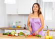 © JackF - Smiling young woman in nightie cooking vegetable salad in kitchen at home.