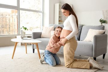 Canvas Print - Young pregnant woman with her little daughter at home