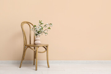 Wall Mural - Blooming branches in vase on chair near beige wall