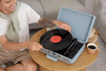 Wall Mural - Young man with record player listening to music at home, closeup