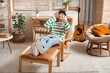 © Pixel-Shot - Handsome young man in headphones listening to music on armchair at home