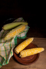 Wall Mural - Clay plate with two cobs sweet corn on wooden background..