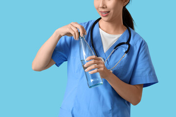 Sticker - Female doctor opening glass bottle of water on blue background, closeup