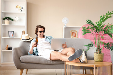 Wall Mural - Male tourist with beer using laptop at home on vacation