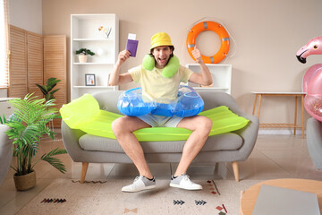 Sticker - Happy male tourist with passport and swim ring showing thumb-up at home on vacation