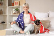 © Pixel-Shot - Young woman with USA flag and pug dog sitting in bedroom