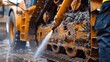 © Justlight - A worker using a pressure washer to clean the engine of a bulldozer removing dirt and debris to prevent potential breakdowns.
