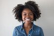 © Pierre - Portrait of young smiling black woman wearing jean shirt with white background.
